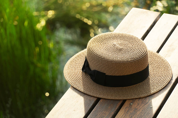 屋外の湖の牧草地と木製のテラスで茶色の旅の女性の帽子太陽の光自然背景 - 写真・画像