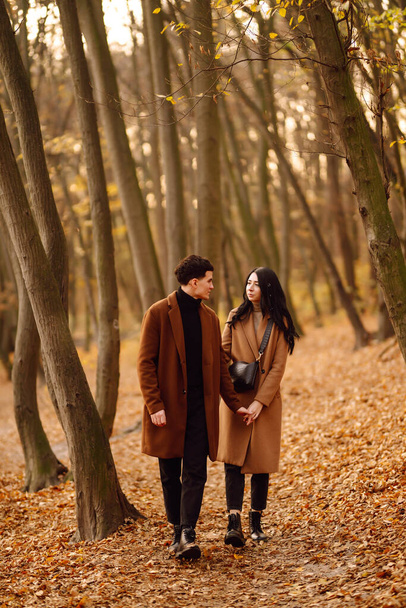 Jeune couple amoureux marchant dans le parc un jour d'automne. Profiter du temps ensemble. Couple élégant et aimant profiter l'un de l'autre dans la forêt d'automne.  - Photo, image