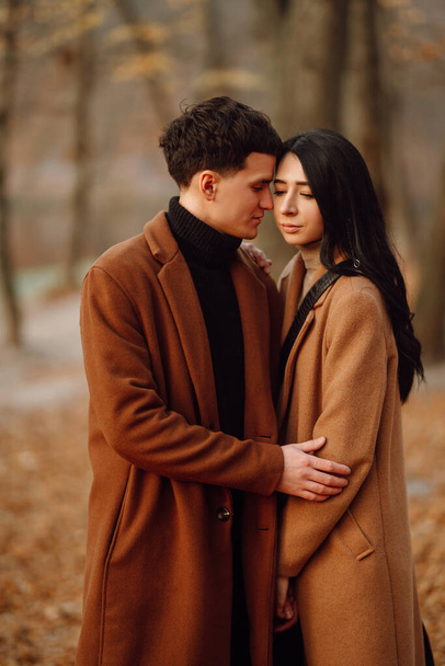 Young couple in love walking in the park on a autumn day. Enjoying time together. Stylish and loving couple enjoying each other in the autumn forest.  - Foto, Imagem