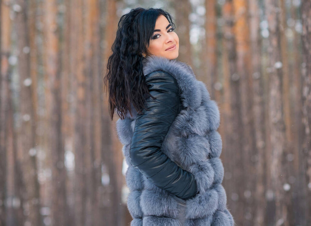 Kobieta w szarym futrze spacer w lesie w zimowy dzień na świeżym powietrzu, panie casual mody - Zdjęcie, obraz