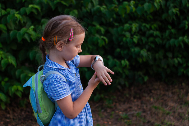 Kluk používající Smartwatch venku v parku. Dítě mluví po telefonu na Vdeo. Školačka používající dotykový displej na hodinkách procházejících internet. Inteligentní náramkové hodinky s GPS trackerem. - Fotografie, Obrázek