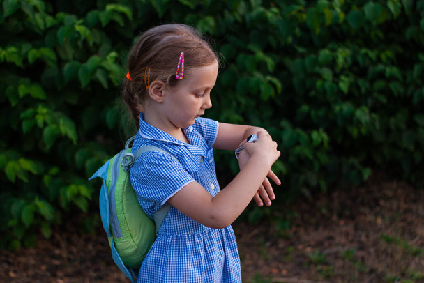 Poika käyttää älykelloa ulkona puistossa. Lapsi puhuu vdeo puhelun älypuhelimeen. Koulutyttö käyttää kosketusnäytön näyttö kellot selaamassa internetissä. Smart rannekello GPS tracker. - Valokuva, kuva