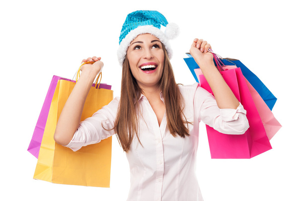 Woman wearing Santa hat holding shopping bags - Foto, Bild