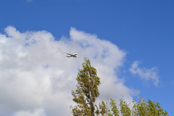 Samolot lecący z niebieskim tłem nieba i zachmurzeniem. Możesz również zobaczyć księżyc w innej kadencji obrazu, w La Corua, Galicja, Hiszpania - Zdjęcie, obraz