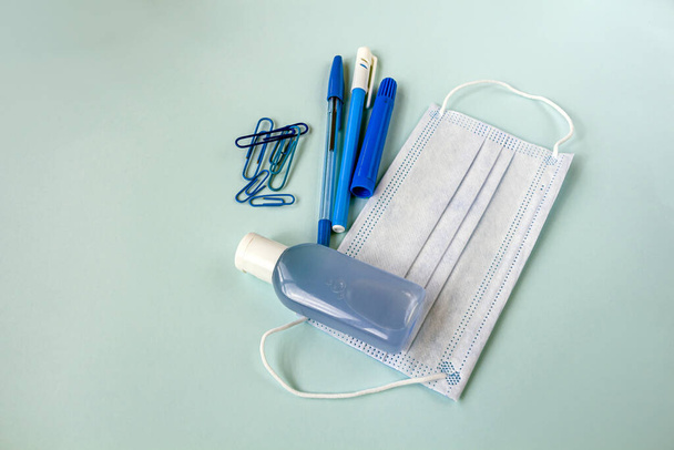 Education or back to school concept. Blue school supplies and medical face mask. New normal during coronavirus pandemic. Virus protection, keep distance. Copy space for text - Photo, image