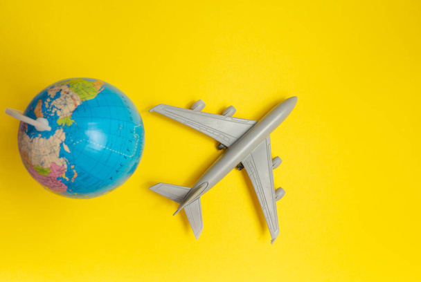 passenger plane on yellow background and globe. traveling by plane - Фото, зображення
