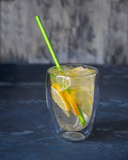 Bebida fría en vaso con paja con cuñas de limón - Foto, imagen