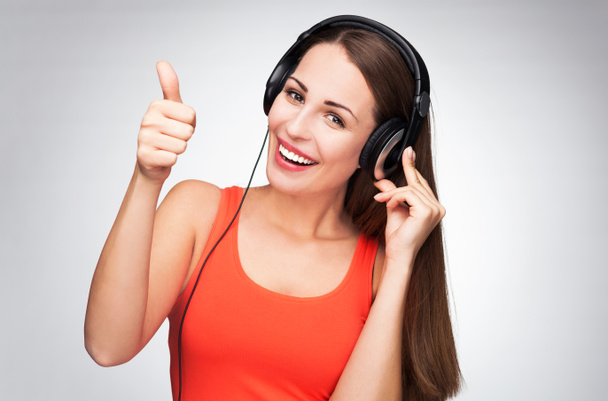 Woman with headphones showing thumbs up - Fotoğraf, Görsel