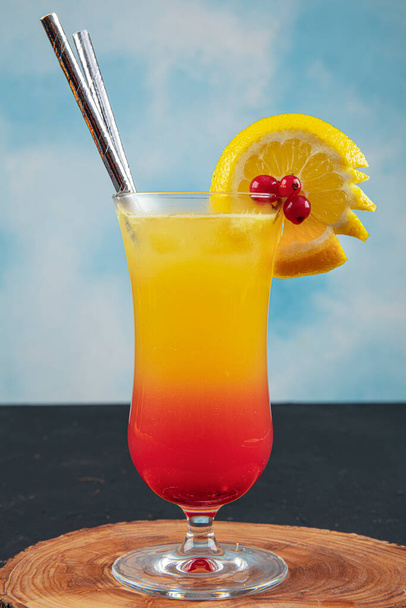 Juicy Orange and Red Tequila Sunrise with a Cherry. Tequila sunrise cocktail on dark wooden table. - Foto, Bild