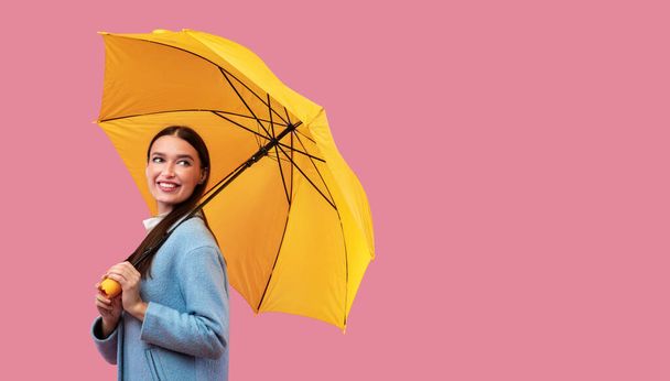 Portrait of cute woman holding umbrella, looking aside - Photo, Image