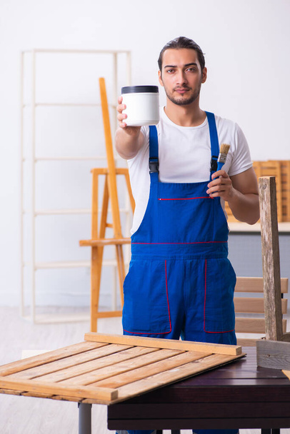 Молодой мужчина-подрядчик работает в мастерской
 - Фото, изображение