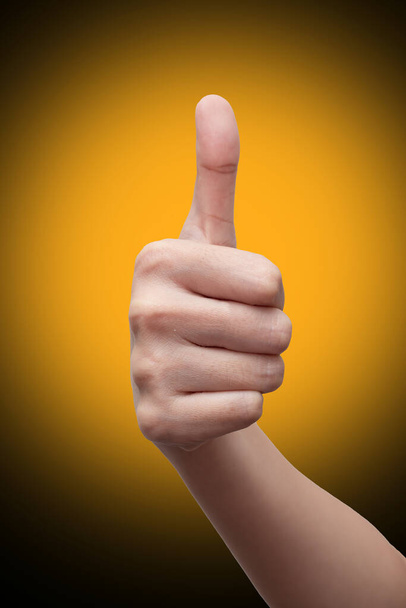 Woman's hand showing thumbs up gesture. isolated on gradient background. Hand sign concept. - Photo, Image