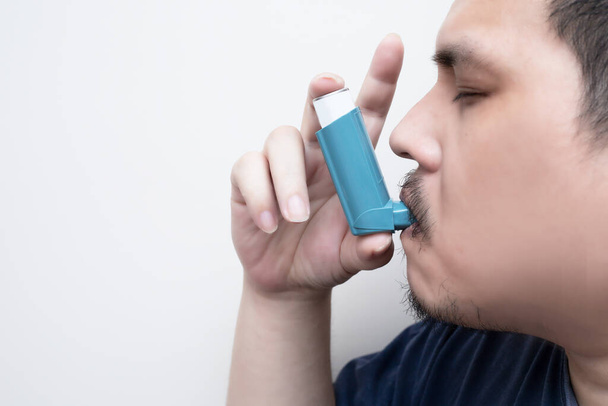 Hombre graso asiático usando un inhalador de cartucho presurizado faringe extendida, broncodilatador. fondo blanco - Foto, imagen