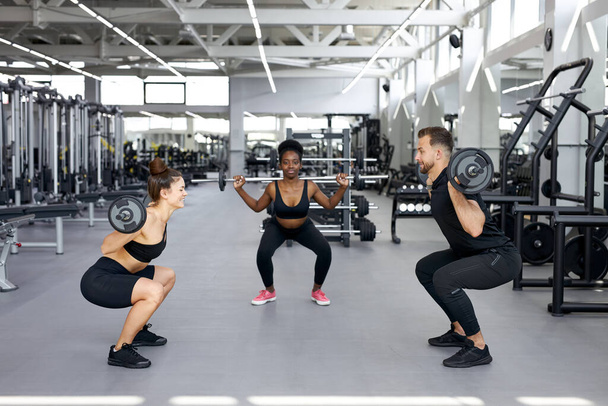 caucasian trainer is teaching exercises with weights to attractive women - Photo, image