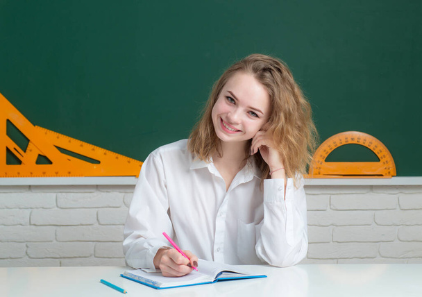 Portrait of smiling teenager girl over blackboard, friendly laughing. Cute college female student in hight school. - Foto, Bild