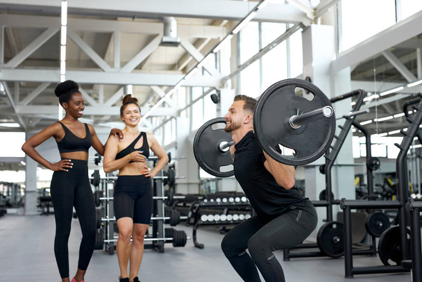 trainer shows exercises with barbell to girls - Photo, image