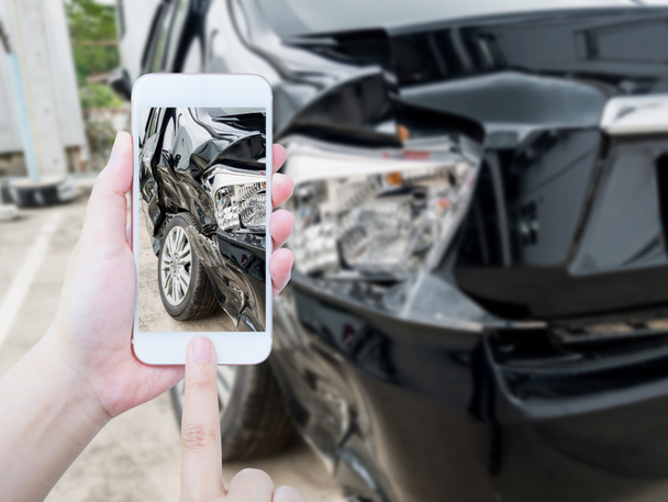 женщина держит мобильный смартфон фотографируя автомобильную аварию для страховки - Фото, изображение