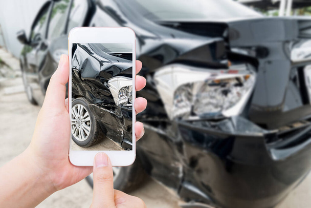 женщина держит мобильный смартфон фотографируя автомобильную аварию для страховки - Фото, изображение