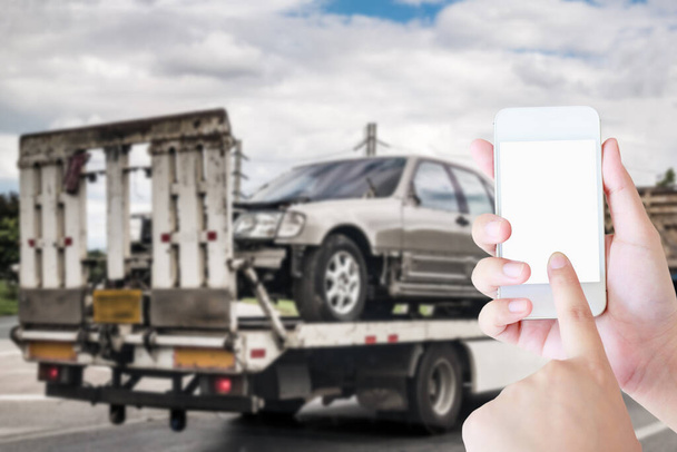 Ruční použití mobilní smartphone pro nouzové silniční služby s rozbitým autem na tahač po dopravní nehodě pozadí - Fotografie, Obrázek