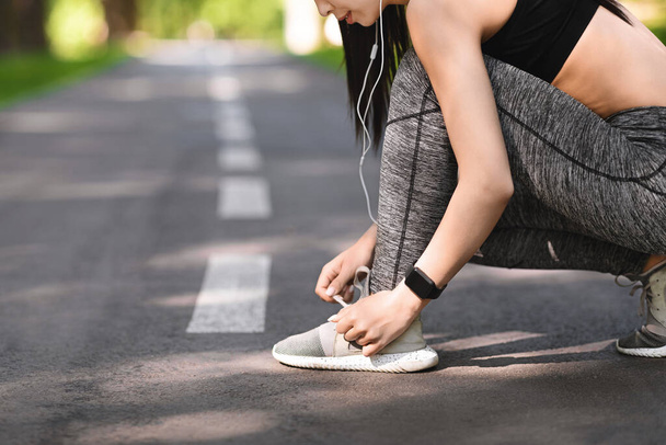 Deportiva chica atando cordones zapatos antes de correr, preparándose para correr al aire libre - Foto, imagen
