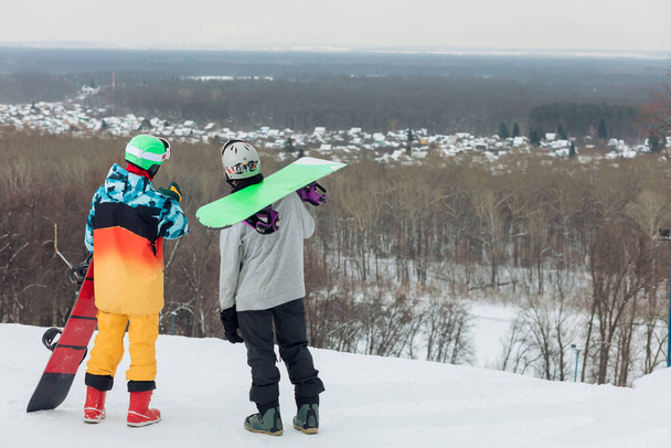 young stylish smen with snowboards having a rest on the top of the mountain - Photo, Image