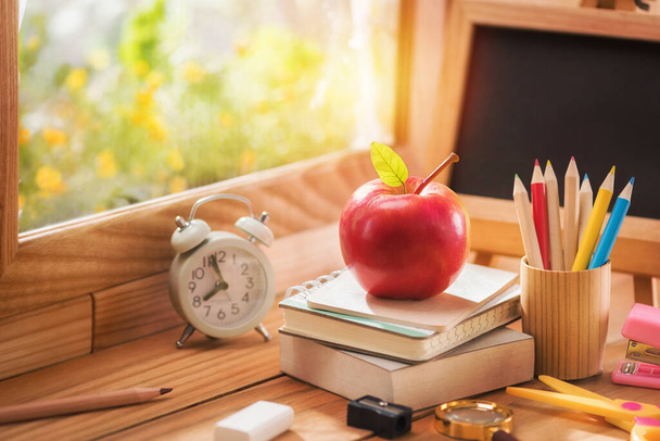 Apple elhelyezett egy könyvet oktatási berendezések mellett az ablak a reggeli fény, Vissza az iskolába koncepció és másolja a helyet. - Fotó, kép