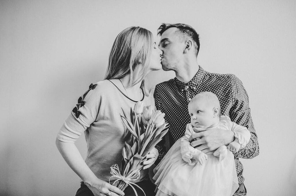 Happy fathers day! Daughter with mom congratulate dad and give her bouquet of flowers. Happy family portrait kissing and hugging, concept love. Mothers, fathers Day. black white photo. - Valokuva, kuva