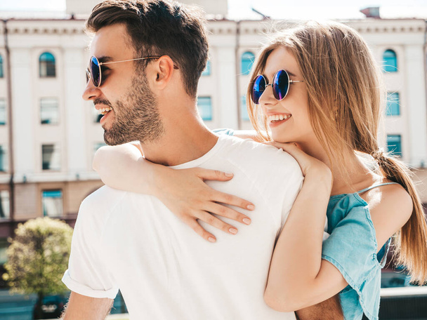 Portrait of smiling beautiful woman and her handsome boyfriend. Woman in casual summer jeans dress .Happy cheerful family. Female having fun. Couple posing on the street background in sunglasses - Фото, зображення