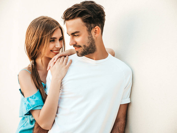 Portrait of smiling beautiful woman and her handsome boyfriend. Woman in casual summer jeans dress. Happy cheerful family. Female having fun. Couple posing near wall - Fotoğraf, Görsel