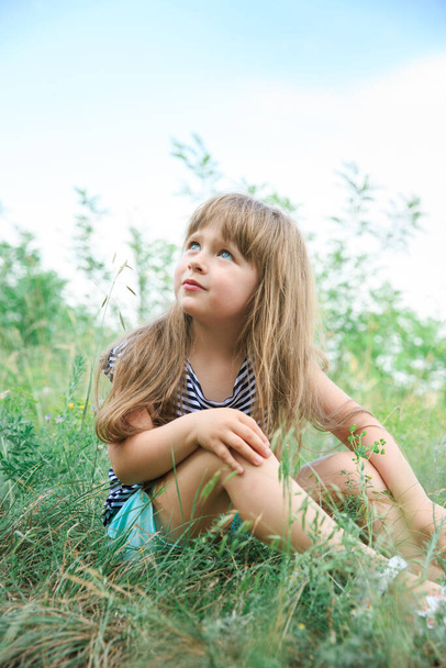 Little girl with long hair sits at the edge of the forest - Foto, Imagem