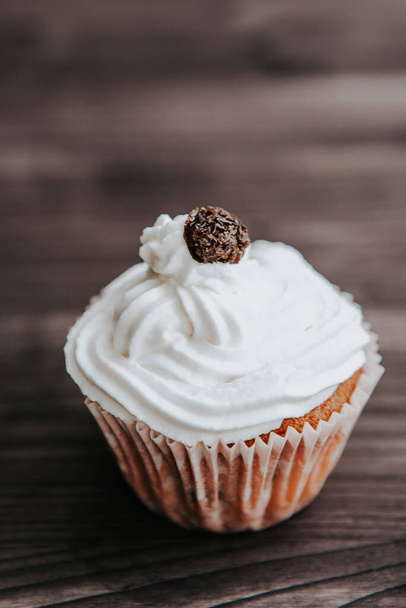 muffin with cream and raisins on a dark wooden background - Photo, image