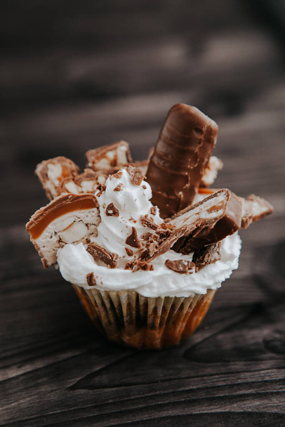 homemade cupcake with white cream and chocolate with nuts on a dark background - Zdjęcie, obraz