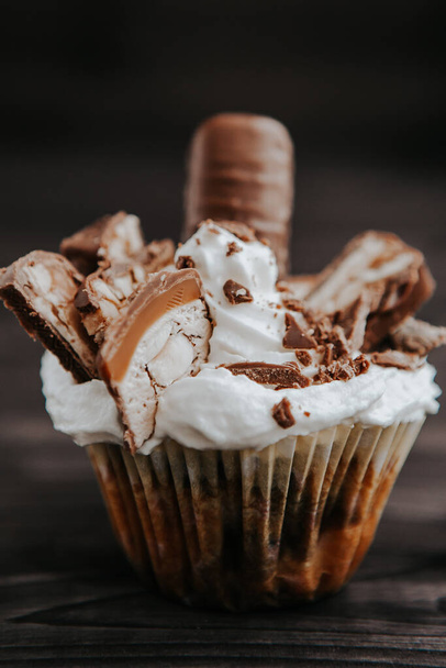 homemade cupcake with white cream and chocolate with nuts on a dark background - Foto, imagen