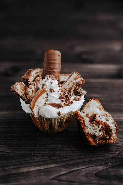 homemade cupcake with white cream and chocolate with nuts on a dark background - Fotó, kép