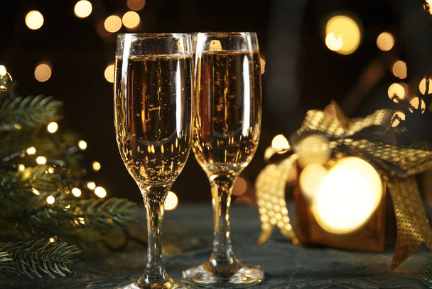 Schleife, Christbaumkugeln und Wein gegen Weihnachtsbeleuchtung - Foto, Bild