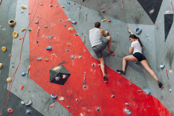 Young couple climbing the wall together. - Foto, imagen