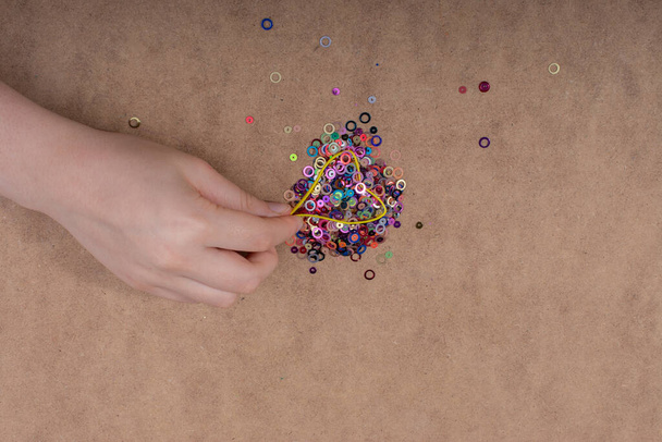 Hand holding decorative shiny colorful confetti on a wooden background - Foto, Bild
