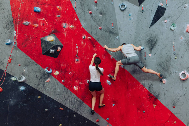 A young man and a woman rock climbing indoors - Fotoğraf, Görsel