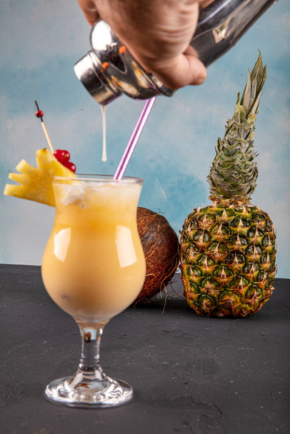 Pina Colada over houten achtergrond gegarneerd ananas. Een cocktail "Kokoskus". - Foto, afbeelding