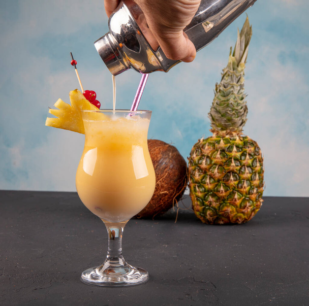Pina Colada over houten achtergrond gegarneerd ananas. Een cocktail "Kokoskus". - Foto, afbeelding