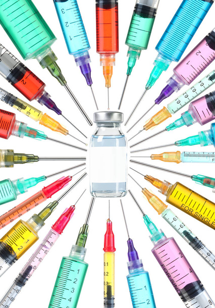 Vakcina ellenszer koncepció. Üres címkével ellátott injekciós üveg, színes fecskendőkkel körülvéve, a vakcina felé mutató tűkkel.. - Fotó, kép