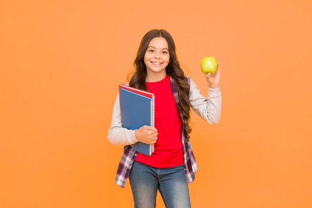 Feed your brain with knowledge. Happy kid hold apple and books orange background. Symbol of knowledge. Back to school. Knowledge day. Education and study. Private teaching. Startup. September 1 - Foto, Bild