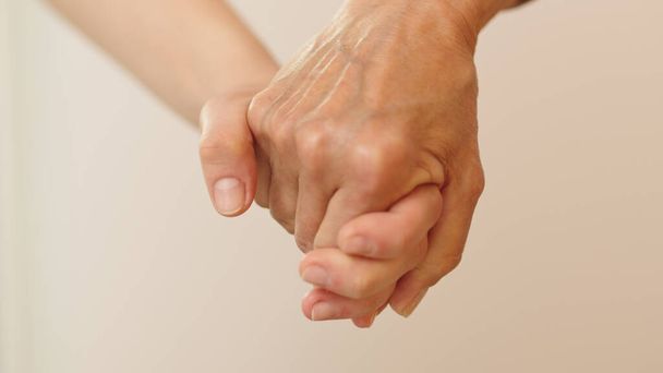 Old and young woman holding hands. Close up, isolated - Foto, afbeelding