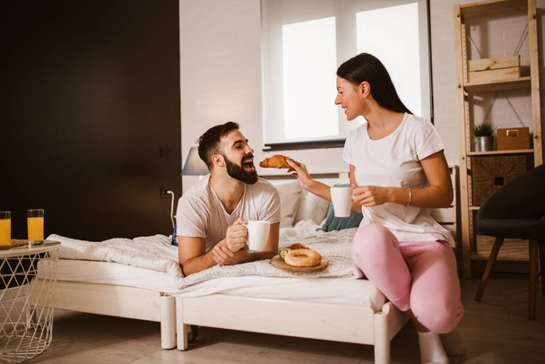 Cute couple having breakfast in bed in the bedroom - Foto, Bild