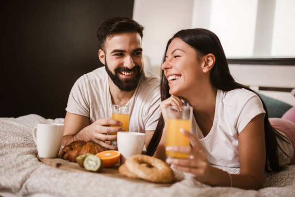Cute couple having breakfast in bed in the bedroom - Photo, Image