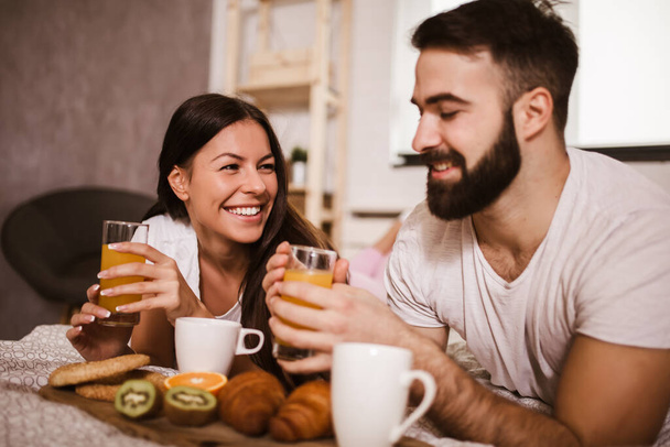 Cute couple having breakfast in bed in the bedroom - Photo, image