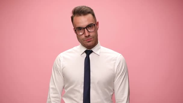 セクシーなエレガントな男で白いシャツを着て眼鏡をかけて両側に頭を傾けるとピンクの背景に笑みを浮かべて - 映像、動画