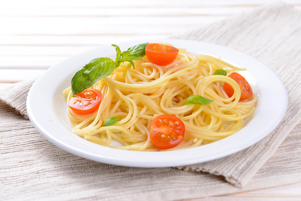 Delicious spaghetti with tomatoes on plate on table close-up - Fotografie, Obrázek