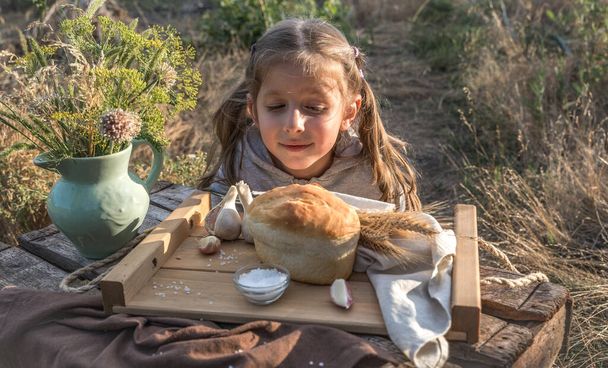 A little girl and bread, still life Breakfast in nature. - Фото, изображение