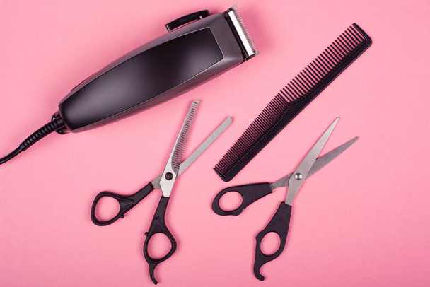 sada nástrojů pro stříhání vlasů na růžovém pozadí, nůžky, hřeben a trimmer - Fotografie, Obrázek